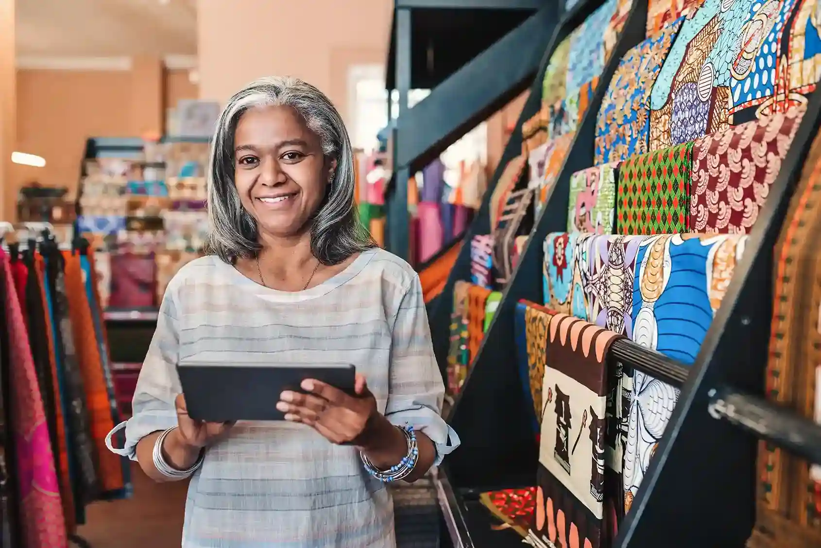 Woman holding a tablet in her fabric shop