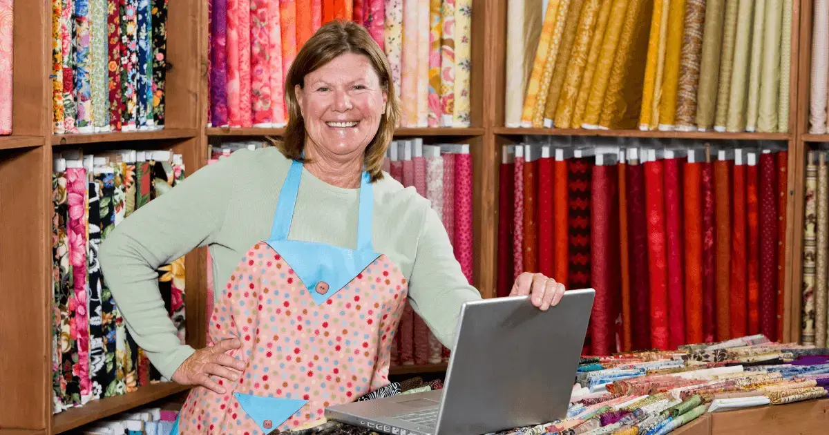 quilt shop owner holding a laptop 